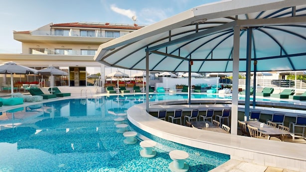 Uma área de piscina com design curvo, espreguiçadeiras e guarda-sóis.