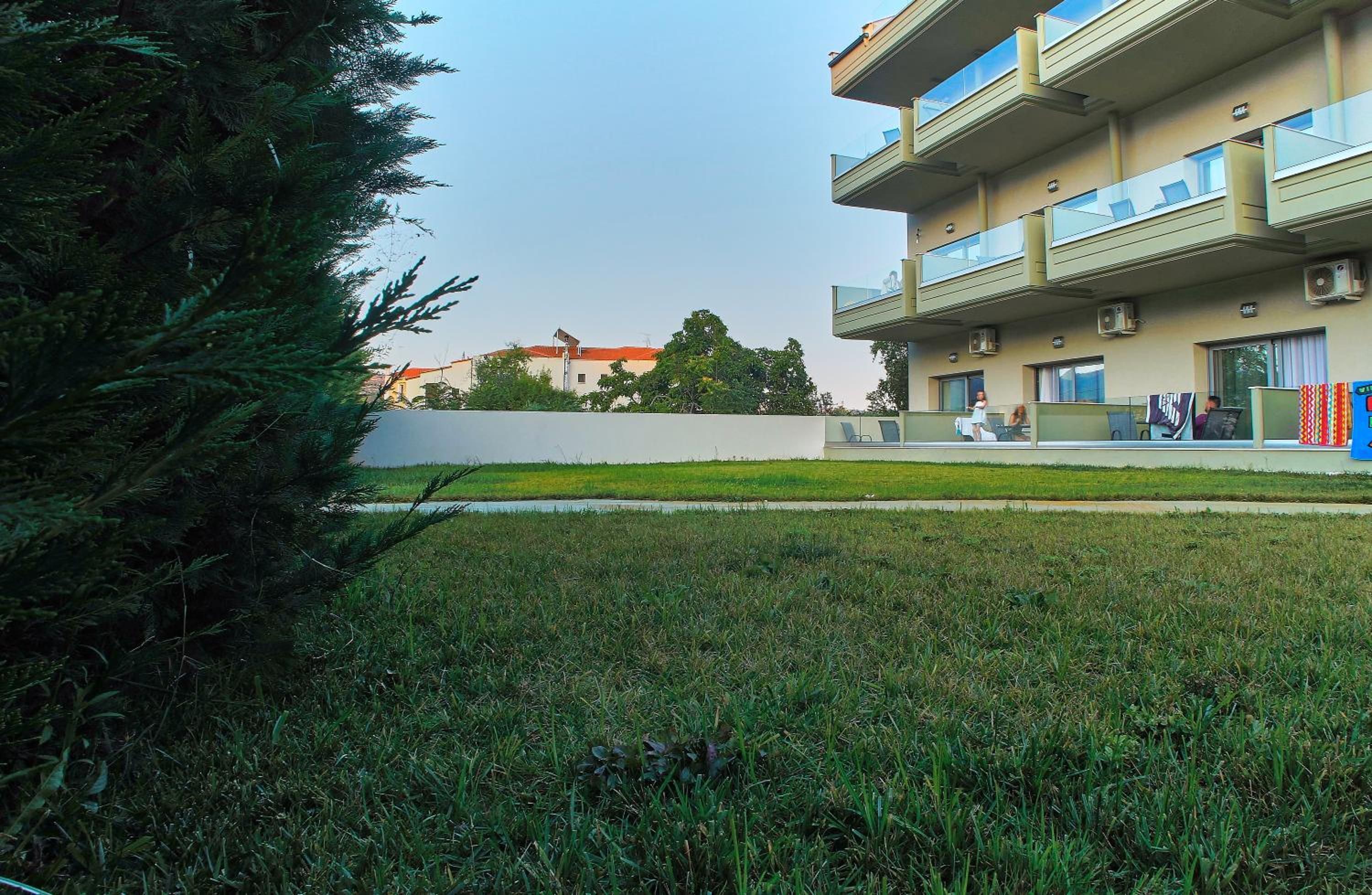Un immeuble résidentiel doté d’un toit plat, de plusieurs balcons et d’une pelouse à l’avant.