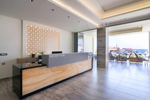 Zona de recepción con mostrador de mármol, pared con diseño y vistas al exterior.
