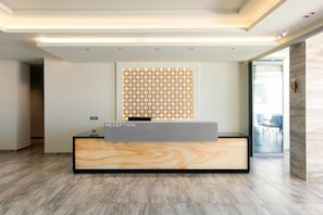 A reception desk with a marble-like design, a patterned wall decoration, and a modern interior. - The Dome Luxury Hotel (Thasos)