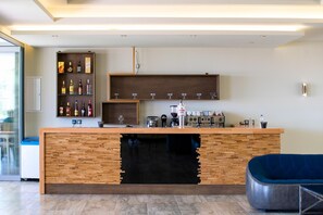 Un área de bar moderna con mostrador de madera, estantes con botellas y una máquina de café.