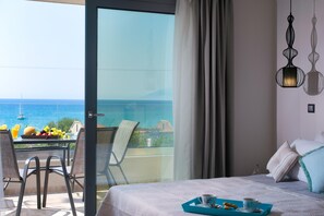 A hotel room with a balcony, a bed with a blue tray, and a table with fruit and a drink. - The Dome Luxury Hotel (Thasos)