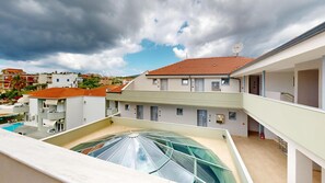 Un immeuble résidentiel doté d’une terrasse sur le toit, de plusieurs balcons et d’une piscine.