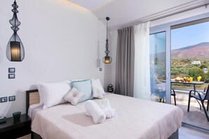 Una habitación de hotel con una cama, una mesita de noche, una mesa con fruta y bebidas, y vistas al paisaje.