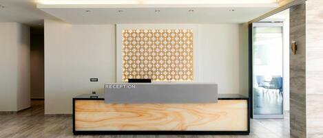 A reception desk with a marble top and a geometric patterned wall behind it.