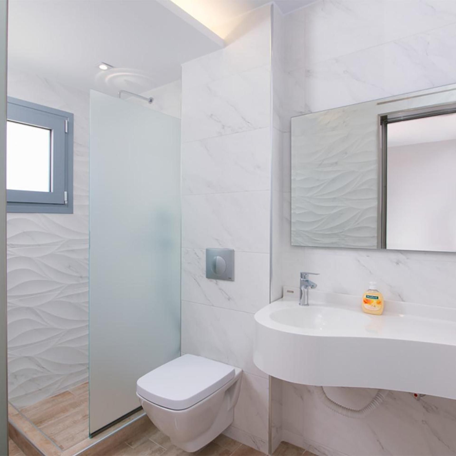 A modern bathroom with a toilet, sink, and shower.