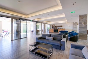 A modern hotel lobby with a seating area, a bar, and a glass-enclosed entrance. - The Dome Luxury Hotel (Thasos)