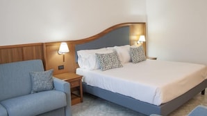 Un dormitorio con cama, dos mesitas de noche y un sofá.