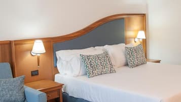 A hotel room with a bed, two bedside lamps, a nightstand, and a chair.