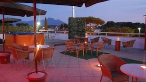Un patio al aire libre con mobiliario de mimbre, una barra y vistas a montañas.