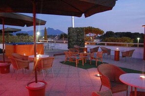 An outdoor patio area with wicker furniture, a bar, and a view of mountains.