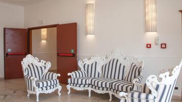 A hotel lobby with striped upholstered chairs and sofas, a wooden door, and wall-mounted light fixtures.