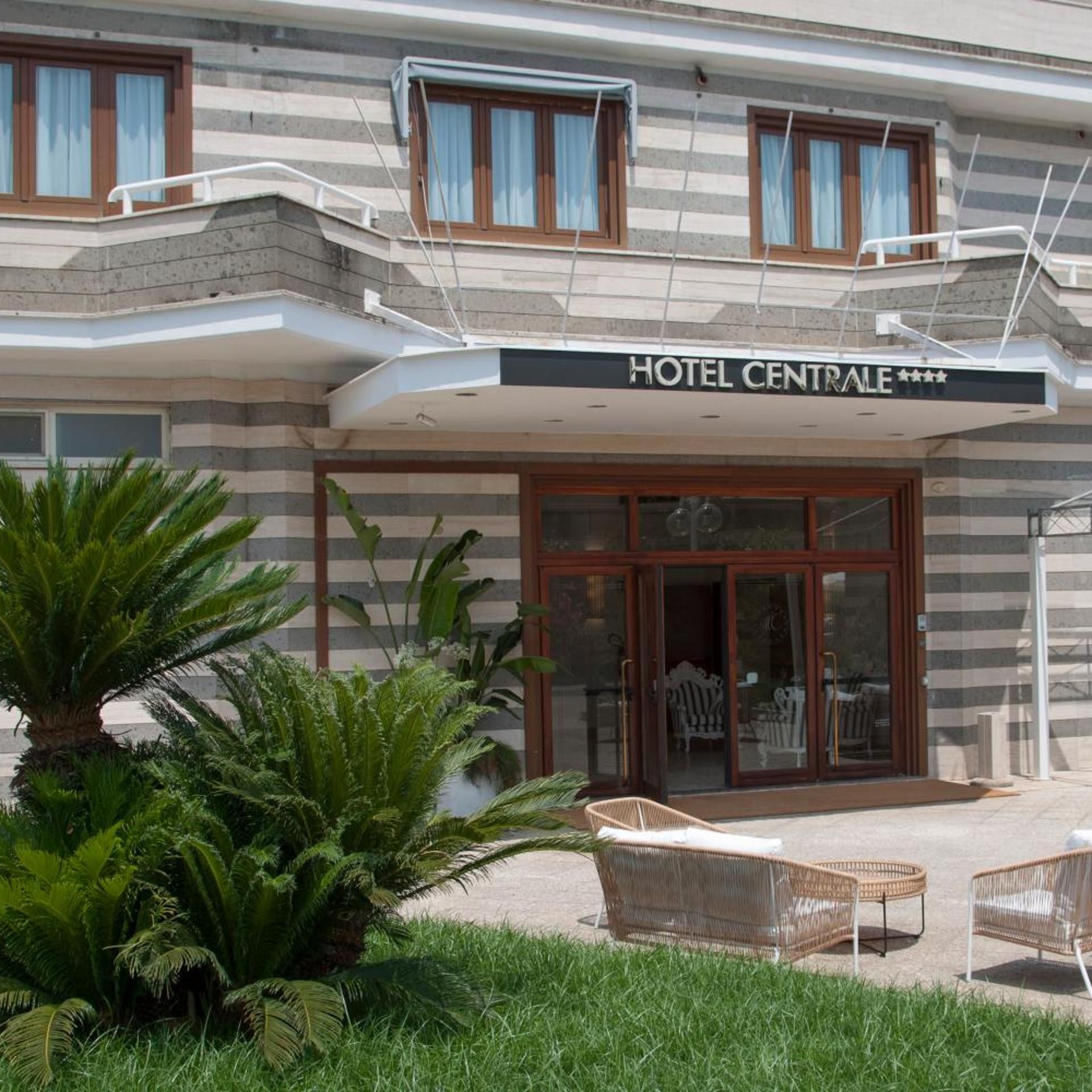 A hotel with a modern facade, a covered entrance, and outdoor seating.