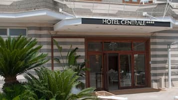 A hotel with a modern facade, a covered entrance, and outdoor seating.