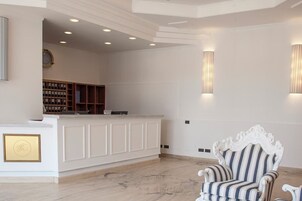 A reception area with a white counter, bookshelves, a clock, and a striped armchair.