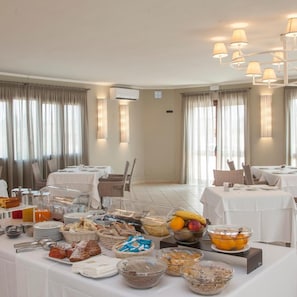 Een restaurantgedeelte van een hotel, met tafels gedekt voor het ontbijt, inclusief diverse gerechten en een buffet.