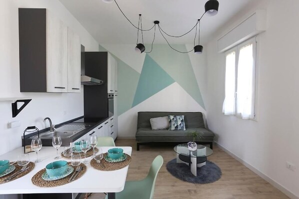 Un espace de vie compact comprenant un coin cuisine, un coin repas et un coin salon.