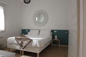 A bedroom with a bed, a bedside table, a wall-mounted mirror, and a window. - Modern suite within walking distance of downtown (Molinella)