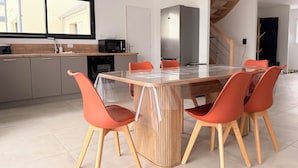 A modern kitchen with a dining table, chairs, and a microwave. - The Liberators - Collection La 21ème Planche (Bayeux)