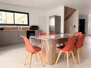 A modern kitchen with a dining table, chairs, and a microwave. - The Liberators - Collection La 21ème Planche (Bayeux)