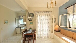 A compact living space with a dining area, kitchenette, and a sofa. - Elena Apartments (Corfu)