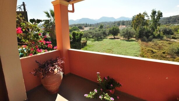 A balcony with a view of a green landscape and mountains in the distance. - Elena Apartments (Corfu)