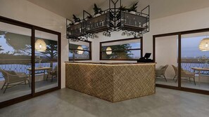 A reception area with a central counter, large windows, and a balcony with wicker chairs. - Cretan Seaside Boutique Hotel (Hersonissos)