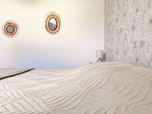 A bedroom with a large bed, two wall-mounted mirrors, a bedside lamp, and a floral-patterned wall. - Les Lavandières - Collection La 21ème Planche (Barbeville)