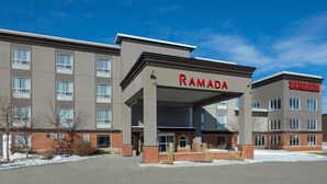A multi-story hotel with a prominent 'RAMADA' sign, a covered entrance, and a 'WATERSLIDE' sign on the right. - Ramada Cochrane (Cochrane)