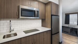 A modern kitchen with a stainless steel refrigerator, microwave, and sink. - Ramada Cochrane (Cochrane)