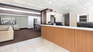 A reception area with a wooden counter, a white sofa, a patterned rug, and a ceiling with a geometric design. - Asheville Airport Inn (Fletcher)