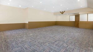 A spacious room with a patterned carpet, beige walls, and recessed ceiling lights. - Asheville Airport Inn (Fletcher)