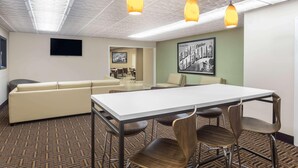 A conference room with a white table, brown patterned carpet, beige sofa, and wooden chairs. - Asheville Airport Inn (Fletcher)