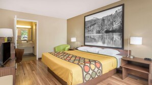 A hotel room with a bed, a desk with a computer, a chair, and a large window with a view of a lake and mountains. - Asheville Airport Inn (Fletcher)