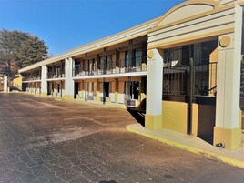 Un hotel con varias habitaciones, un estacionamiento y cielo despejado.