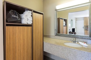 Un bagno d'hotel con un mobile bagno in legno, un lavandino e uno specchio.