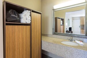 Un baño de hotel con tocador de madera, lavamanos y espejo.