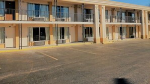 A multi-story motel with balconies, large windows, and a parking lot. - Asheville Airport Inn (Fletcher)