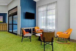 A modern room with a flat-screen TV mounted on the wall, a glass door leading outside, and a green carpet.