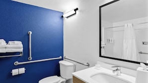 Et badeværelse med et hvidt toilet, en vask med et spejl over og en blå væg.
