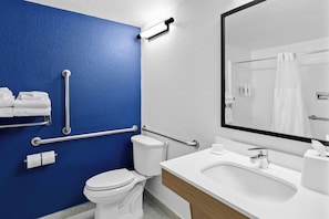 Casa de banho com sanita branca, lavatório com espelho em cima e parede azul.