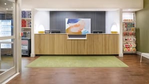 En reception med en træreception, et stort abstrakt maleri over, og reoler med diverse genstande på hver side.