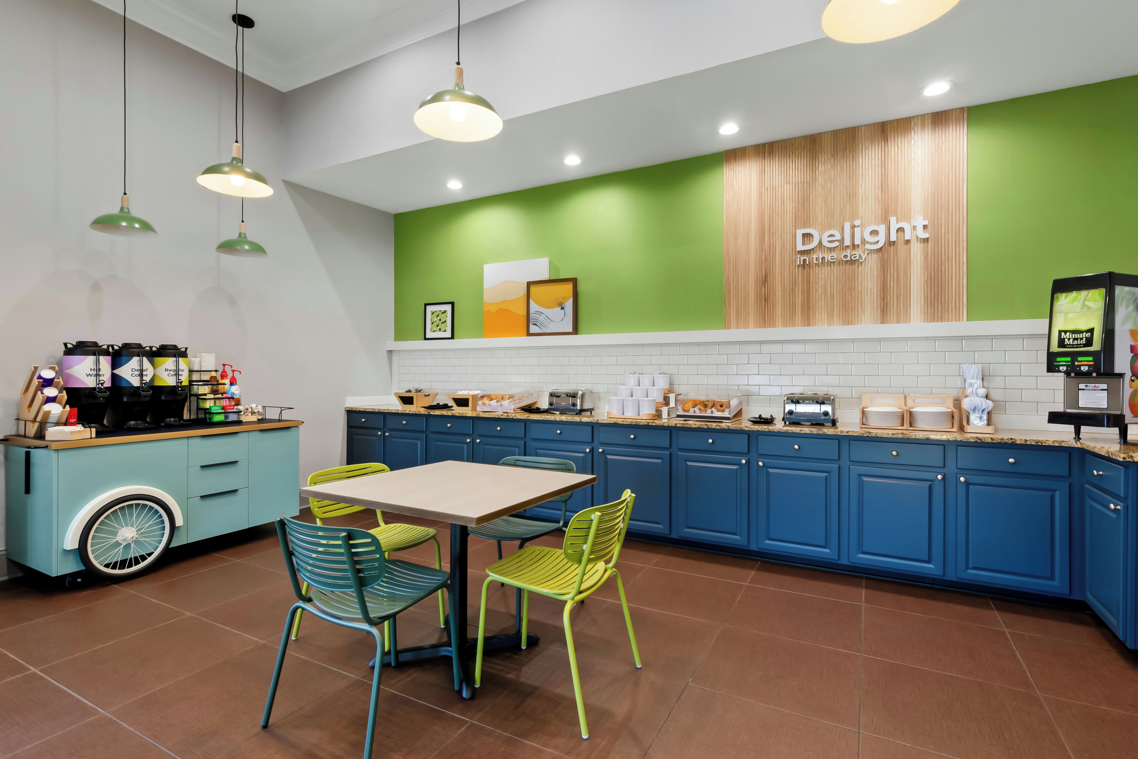 A modern cafe interior with a green accent wall, a coffee station, and a seating area with colorful chairs.