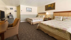 Habitación de hotel con dos camas, un escritorio con silla, televisión y microondas.