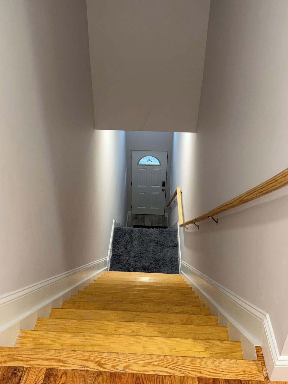 A wooden staircase leading to a door with a frosted glass window.