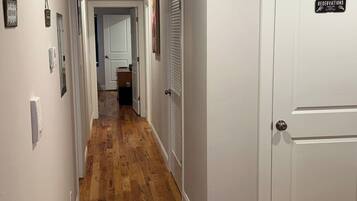 Un pasillo con piso de madera, paredes blancas y una puerta cerrada con un letrero que dice 'RESERVATIONS'.