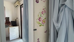 A room with a bed, a desk with a computer, and a wardrobe with floral decorations. - Seafront Studio Apartment with Balcony (Podgora)