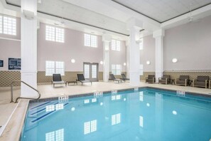 An indoor swimming pool with clear lane markings, lounge chairs, and a tiled floor. - Country Inn & Suites by Radisson, Manchester Airport, NH (Bedford)