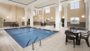 An indoor swimming pool with a tiled floor, white columns, and multiple tables and chairs. - Country Inn & Suites by Radisson, Manchester Airport, NH (Bedford)