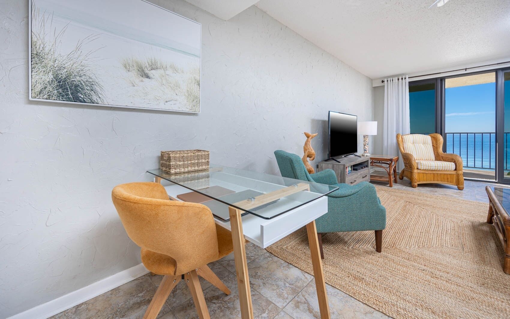 A modern living room with a glass table, two chairs, a TV, and a wicker basket.